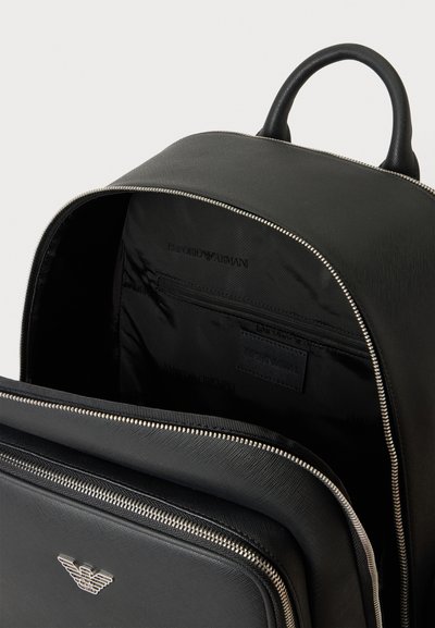 Sac à dos Emporio Armani noir avec compartiments principal et avant à fermeture éclair ouverts, montrant le logo sur la poche extérieure et une poignée sur le dessus.