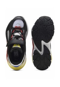 Chaussures de sport noires et blanches avec des accents rouges ; tige en mesh, languette rembourrée, bride Velcro et semelle extérieure épaisse en caoutchouc noir avec motif ondulé.