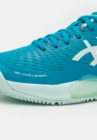 Sapatilha de ténis teal com parte superior texturizada, ponta reforçada e amortecimento GEL. Sola de borracha com padrão de aderência para tração.