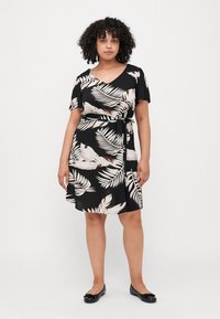 Black dress with short sleeves featuring a white and beige leaf pattern, a v-neckline, and a tied waist detail, made of lightweight fabric.