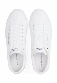 Sneaker bianche in tela con lacci piatti, soletta imbottita e un logo sul lato e sulla linguetta. Presentano un design minimalista e punta arrotondata.