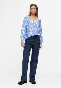 Lys blå v-hals bluse med creme leopardmønster, lange puf ærmer, parret med mørke denim lige bukser og sorte chunky sko.