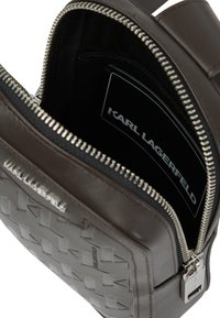 Brązowa skórzana torba na ramię z teksturowanym wzorem plecionki, srebrnymi elementami metalowymi i zapięciem na zamek. Wnętrze z etykietą marki.