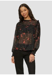 Schwarze durchsichtige Bluse mit floralen Mustern in Rot und Gelb, plissierte Textur, Volant-Ausschnitt und elastische Bündchen. Getragen mit schwarzen Hosen.