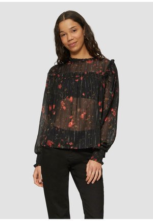 Schwarze durchsichtige Bluse mit floralen Mustern in Rot und Gelb, plissierte Textur, Volant-Ausschnitt und elastische Bündchen. Getragen mit schwarzen Hosen.