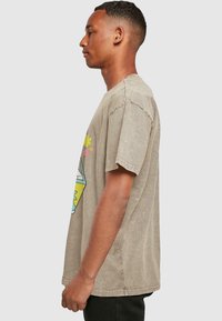 Camiseta de algodón beige con un diseño gráfico colorido que presenta flores y formas geométricas. Mangas cortas y un corte relajado.