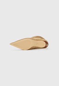 Decolleté beige in suede con punta affusolata, superficie liscia, suola in gomma texturizzata e design snello. Il tacco è alto circa 10 cm.