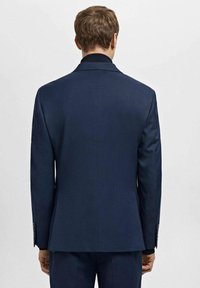 Marineblauer taillierter Blazer aus strukturiertem Stoff, mit einer einzelnen Rückennaht und Revers mit Kerbkragen. Verfügt über dezente Nähte entlang der Ärmel und klare Linienführung.