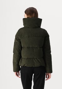 Jachetă puffer din catifea închisă, de culoare verde, cu guler înalt, secțiuni umflate și material texturat. Dispune de mâneci lungi și o talie ajustată.