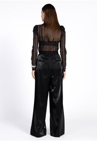 Zwarte sheer gestreepte blouse met lange mouwen, gecombineerd met zwarte glanzende hoge taille wijde broek, met achterzakken en een zachte textuur.