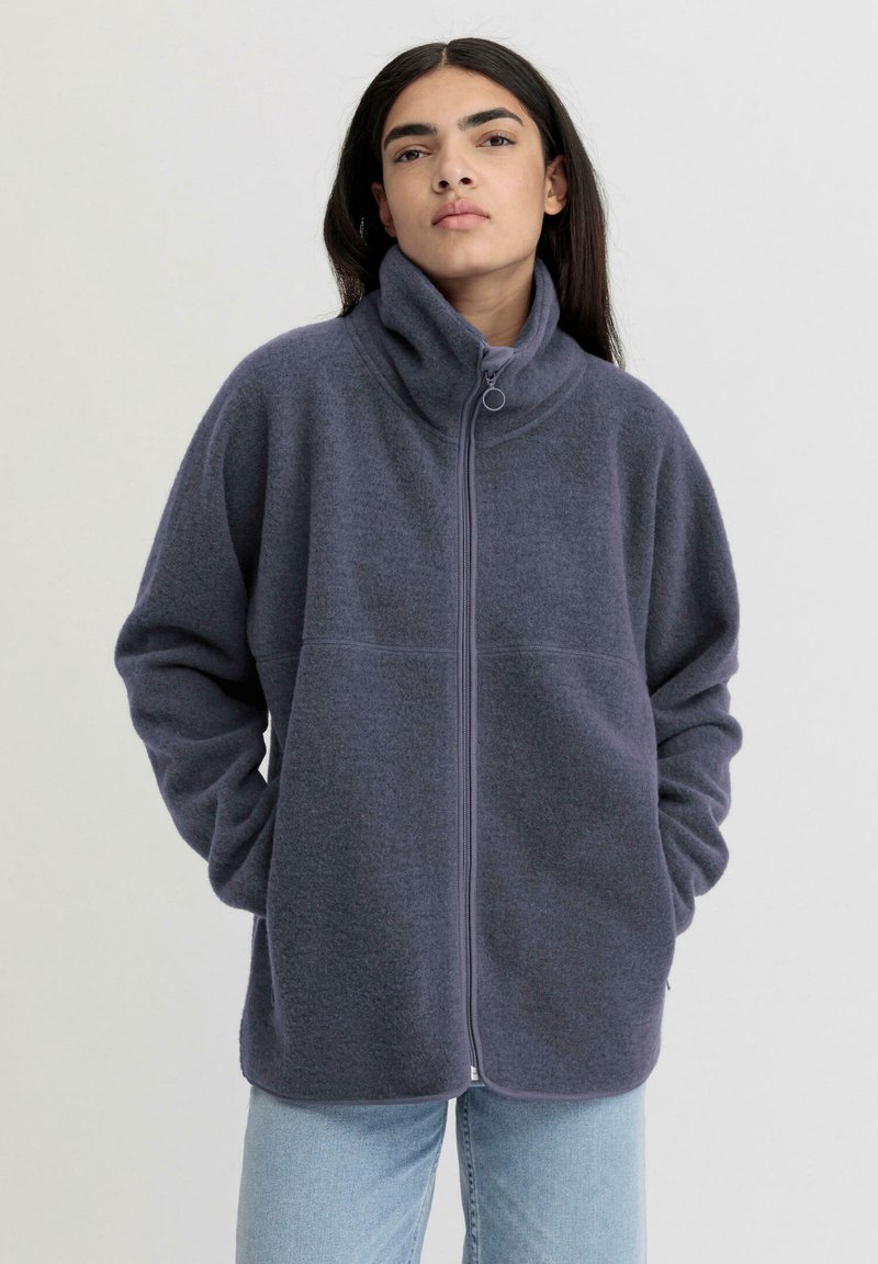 Giacca in pile blu scuro con colletto alto, zip frontale e vestibilità comoda. Maniche lunghe e tasche laterali ne aumentano la funzionalità.