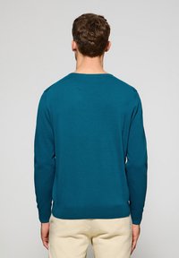 Türkisfarbener Strickpullover mit langen Ärmeln und Rundhalsausschnitt. Verfügt über einen gerippten Saum und Bündchen und zeichnet sich durch eine glatte Textur aus.