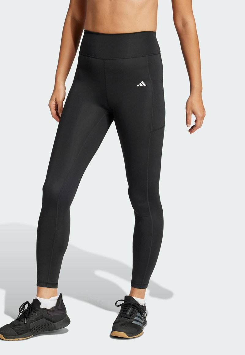 Sorte sportsleggings med høj talje, der har en glat overflade, flade sømme og et Adidas-logo på venstre hofte.