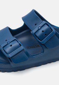 Sandali Birkenstock blu con due cinturini regolabili, una tomaia in sintetico testurizzato e un plantare sagomato per il comfort.