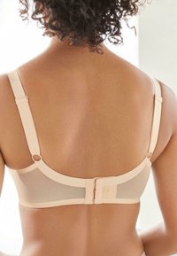 Beige beha met netdetails, verstelbare bandjes en een haak-en-oogsluiting aan de achterkant. Glad materiaal met minimale hardwareaccenten.