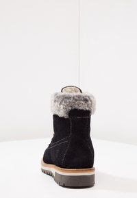 Schwarzer Wildlederstiefel mit einem grauen Kunstfellkragen, robuster Sohle und sichtbarem Stichdetail. Die Rückansicht hebt das Design und die Textur hervor.
