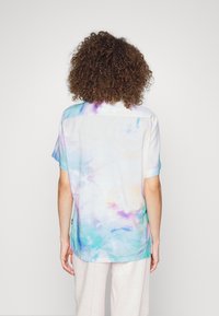 Maglietta a maniche corte con effetto tie-dye caratterizzata da colori pastello di blu, rosa e giallo. Tessuto leggero con una vestibilità rilassata e orlo curvo.