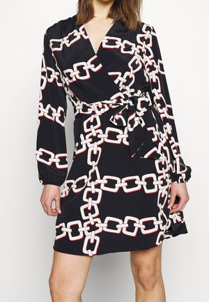 Robe portefeuille noire à manches longues avec un motif chaîne blanc, nouée à la taille avec une ceinture en tissu assortie.