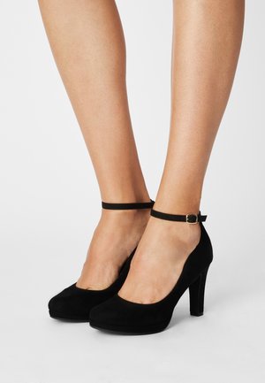 Chaussures à talons hauts en daim noir avec une bride de cheville et une boucle dorée. Design à bout rond et texture lisse.