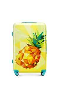 Valise rigide avec un fond jaune, motif en ananas géométrique aux couleurs orange et verte, accents teal, et quatre roues.