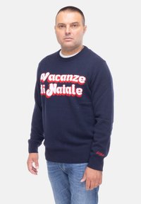 Maglione lavorato a maglia blu navy con la scritta bianca e rossa "Vacanze di Natale" sul davanti, con polsini e fondo a coste.