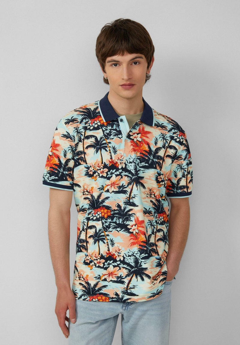 Polo à manches courtes avec un motif de fleurs tropicales multicolores et de palmiers. Base bleu clair avec un col et des accents bleu foncé.