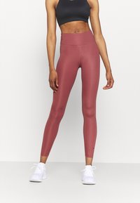 Leggings taille haute, ajustés et en rose doux, fabriqués à partir d'un matériau extensible, présentant un design sans coutures et un léger détail de logo.