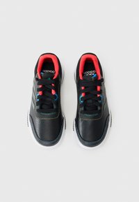 Chaussures de sport noires avec une tige en cuir texturé, des accents colorés en rouge et bleu, un motif rayé et des semelles en caoutchouc blanches.