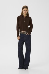 Bruine, korte mouwen polo met een kraag en knoopsluiting; gecombineerd met loszittende, donkerblauwe spijkerbroeken en een grijze riem.