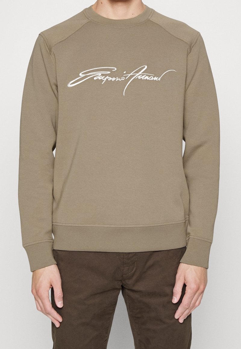 Kaki sweatshirt med långa raglanärmar, rund halsringning och en vit signaturlogo över bröstet, med texturerad tyg.
