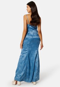 Sukienka maxi w kolorze satynowego niebieskiego z ramiączkami typu spaghetti, kwiatowym wzorem i dopasowanym krojem. Teksturowany materiał o gładkim wykończeniu.