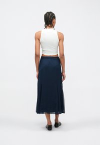 Λευκό αμά νικο crop top συνδυασμένο με φουλάρι μακρύ navy. Η φούστα διαθέτει ελαστική μέση, υφή ύφανσης και σχεδιασμό μέχρι τον αστράγαλο.