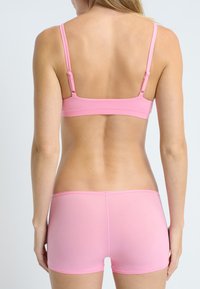 Sujetador deportivo rosa con tirantes ajustables, combinado con unos pantalones cortos a juego. Hecho de una tela suave y elástica, presenta líneas limpias y costuras mínimas.