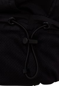 Tissu noir avec cordon de serrage passant à travers deux œillets métalliques et fixé avec un verrou cylindrique.