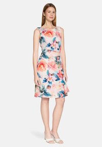 Robe fleurie en tissu rose clair, ornée de fleurs et de feuilles multicolores, sans manches, avec une jupe à la silhouette évasée.