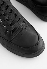 Czarne skórzane sneakersy z teksturowanymi sznurówkami, perforowanymi bocznymi panelami i gładką nakładką na palce. Oferują kontrastowe przeszycia wzdłuż podeszwy.