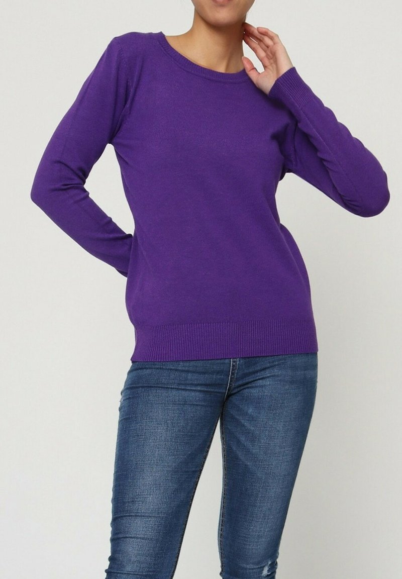 Pull en maille violet à manches longues, col rond, avec un ourlet et des poignets côtelés ; associé à un jean bleu, mettant en valeur une coupe ajustée.