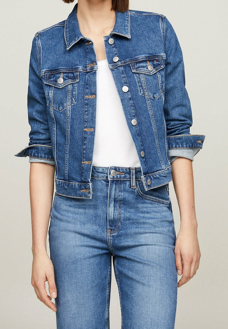 Jeansjacka i medelblått, med bröstfickor, silverknappar och uppvikta ärmar. Kombinerad med ljusblå högmidjade jeans.