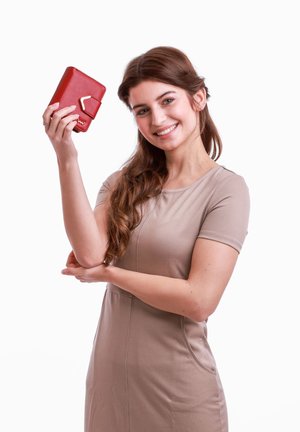 Red leather wallet with a textured finish and geometric hardware detail, held in a person's hand. Plain beige dress. White background.
