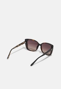 Cat-eye sunglasses with a dark tortoiseshell frame and gradient brown lenses. Temples feature a leopard print pattern.