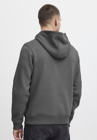 Gray hoodie made of soft fabric featuring a drawstring hood, ribbed cuffs, and hem, with a plain finish and no visible logos.
