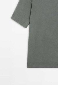 Pull en maille gris à manches courtes avec motif texturé, poignets et ourlet côtelés, posé à plat sur une surface blanche.