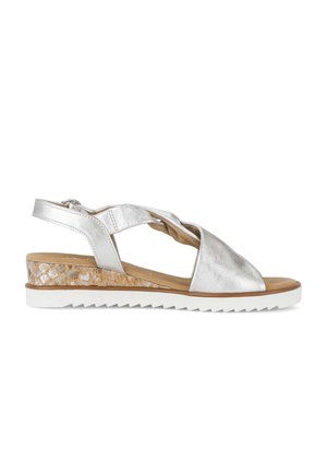 Women's silver leather sandal with crisscross straps, cork wedge heel, white ridged sole, and adjustable ankle strap buckle.