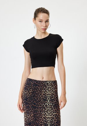 Schwarz gekürztes T-Shirt mit kurzen Ärmeln, kombiniert mit einem Rock im Leopardenmuster in verschiedenen Braun- und Cremetönen. Glatte Textur.