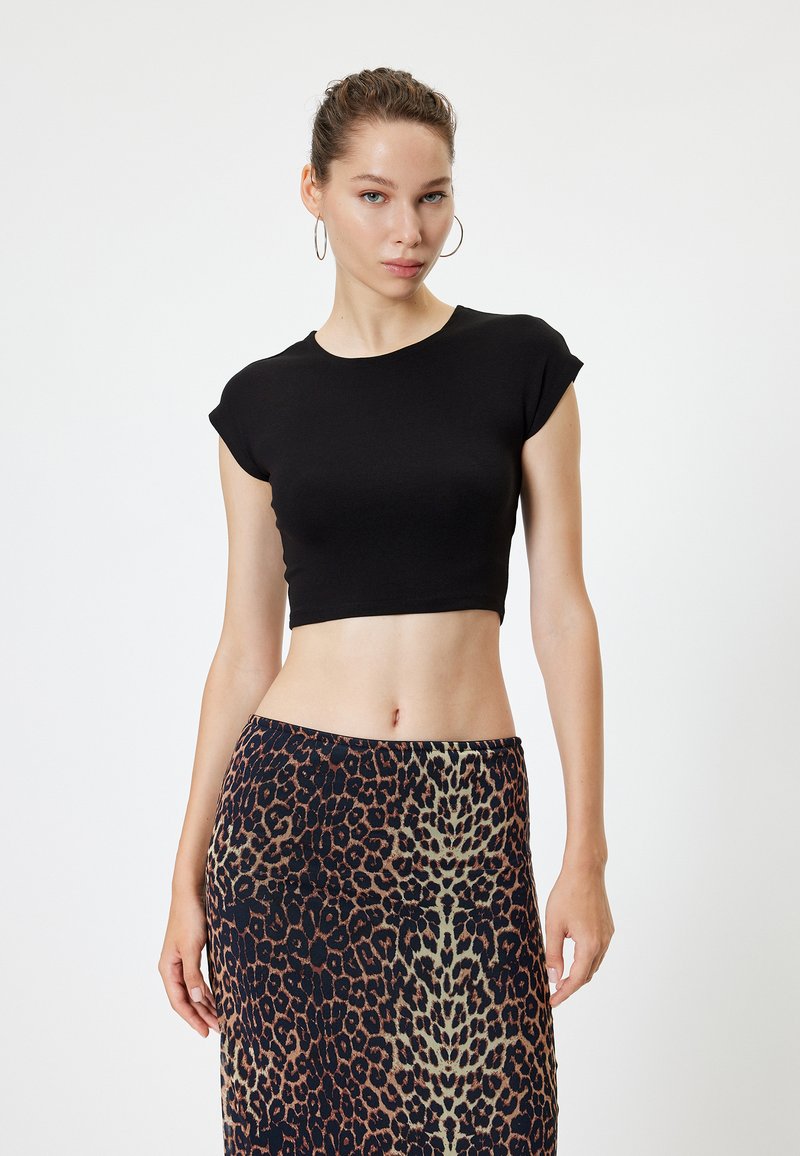 Schwarz gekürztes T-Shirt mit kurzen Ärmeln, kombiniert mit einem Rock im Leopardenmuster in verschiedenen Braun- und Cremetönen. Glatte Textur.