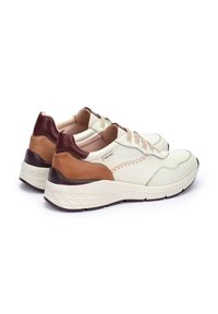 Zapatillas de cuero en color crema con acentos en marrón y terracota. Forma redondeada, paneles laterales texturizados y suelas acolchadas. Diseño con cordones.