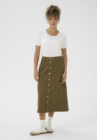 Green corduroy midi skirt with a front button closure, two side pockets, paired with a white ribbed top and white sneakers.