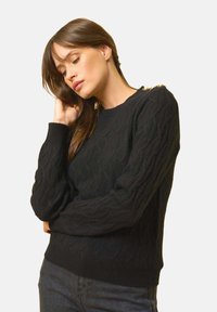 Czarny sweter we wzór w warkocze z długimi rękawami, ściągaczami przy mankietach i u dołu, oraz złotymi akcentami na ramionach. Miękka tkanina i dopasowany krój.