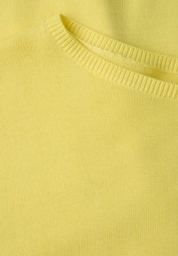 Gelbes Strickpullover mit geripptem Ausschnitt, der eine glatte, strukturierte Oberfläche und subtile Nähte aufweist.