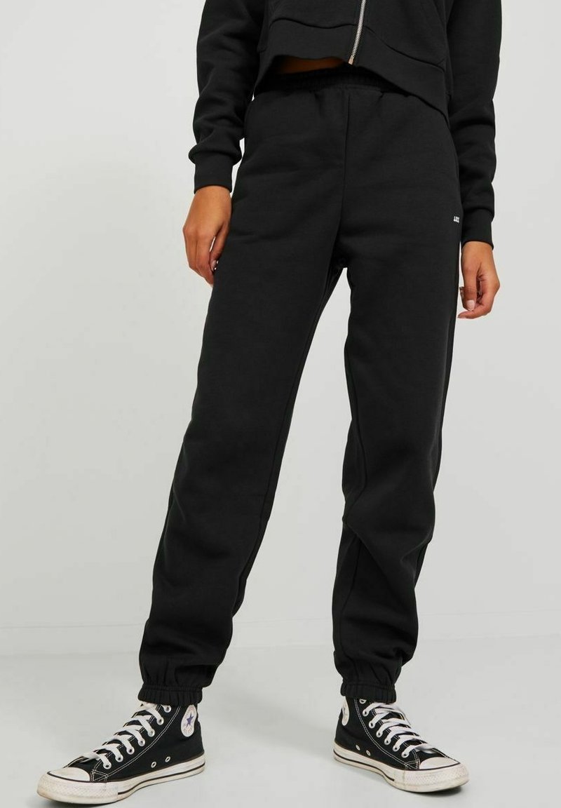 Black sweatpants made of soft fabric, featuring an elastic waistband, tapered cuffs, and a small logo detail on the front side.